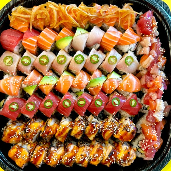 A large platter of various Sushi Friend sushi rolls, including salmon, tuna, and eel.