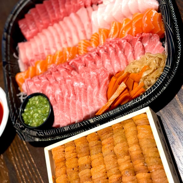 A large platter of various sashimi, including tuna, salmon, and white fish, with a side of uni.